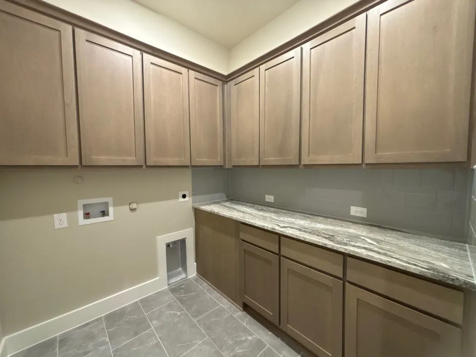 Cabinetry with wood-finish doors, durable stone-finish countertop, subway tile backsplash, and tile flooring