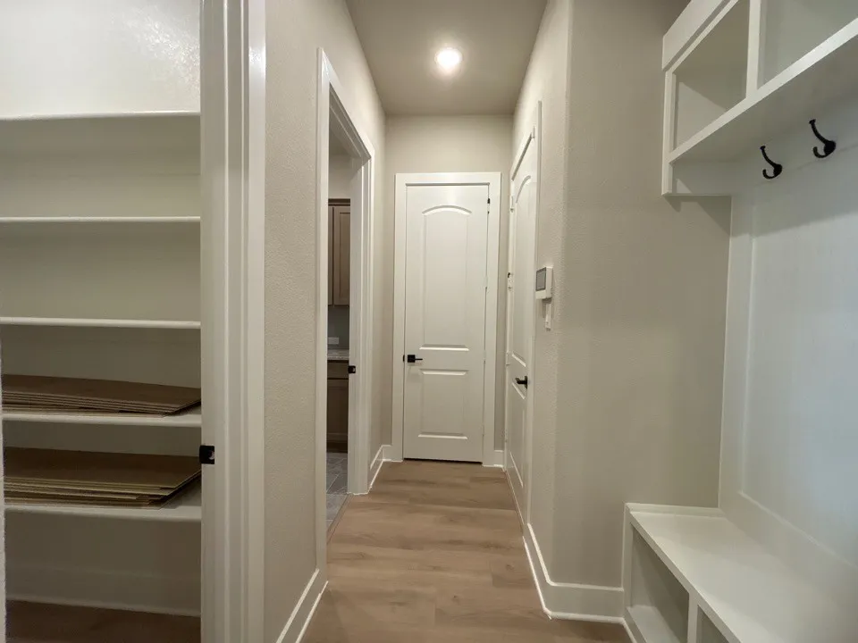Wood-finish flooring, built-in shelving, white paneled doors, and a built-in bench with storage