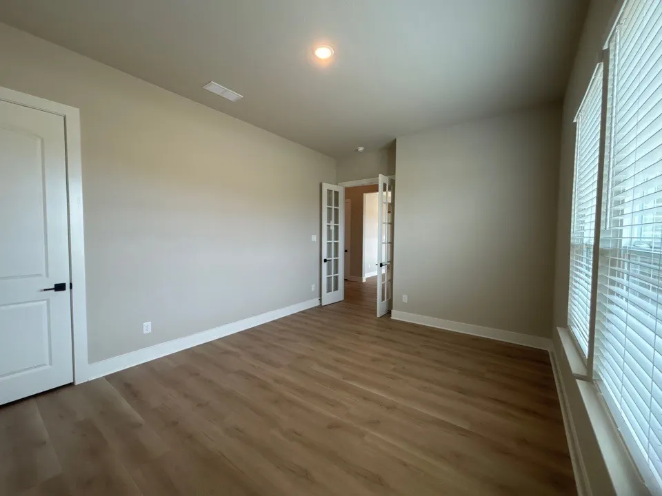 Wood-finish flooring, neutral wall tones, white trim, and white doors with matte black hardware