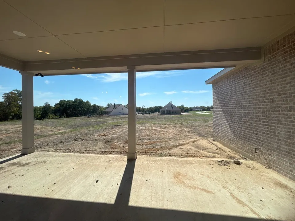 Covered concrete patio with recessed lighting and brick exterior wall