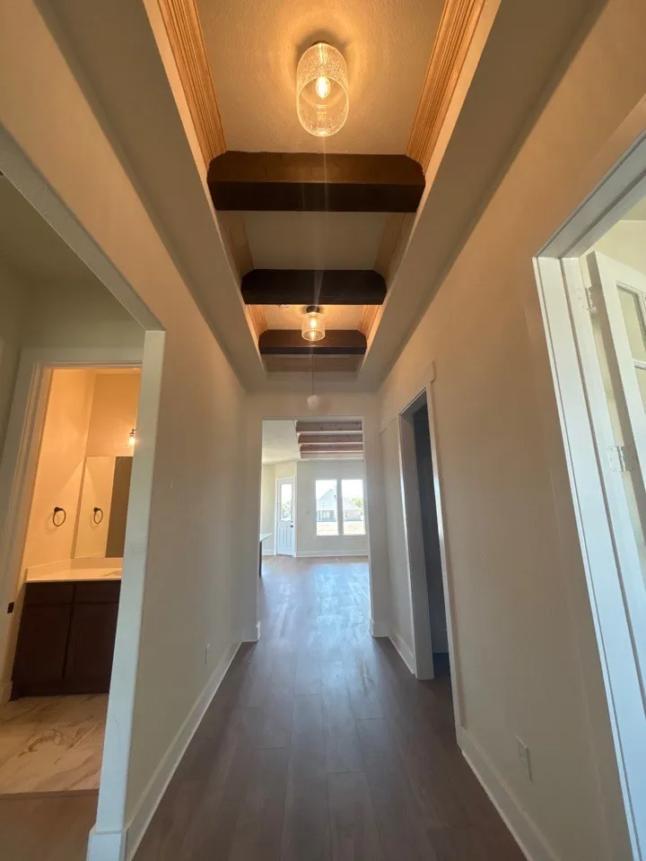 Hallway featuring wood-finish flooring, decorative ceiling beams, recessed lighting, and a neutral color palette