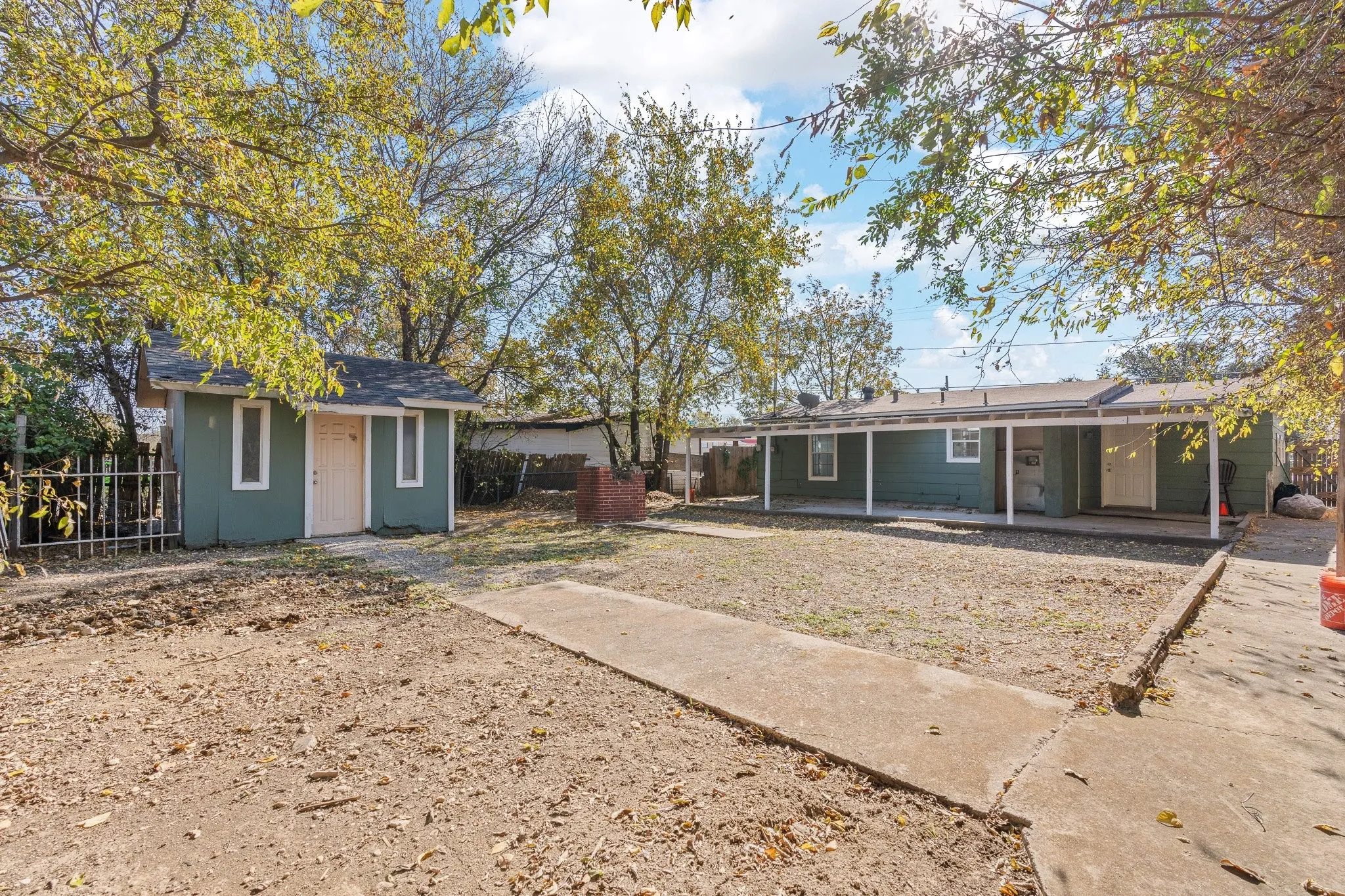 Expansive backyard space featuring a covered patio, separate storage shed, and mature trees