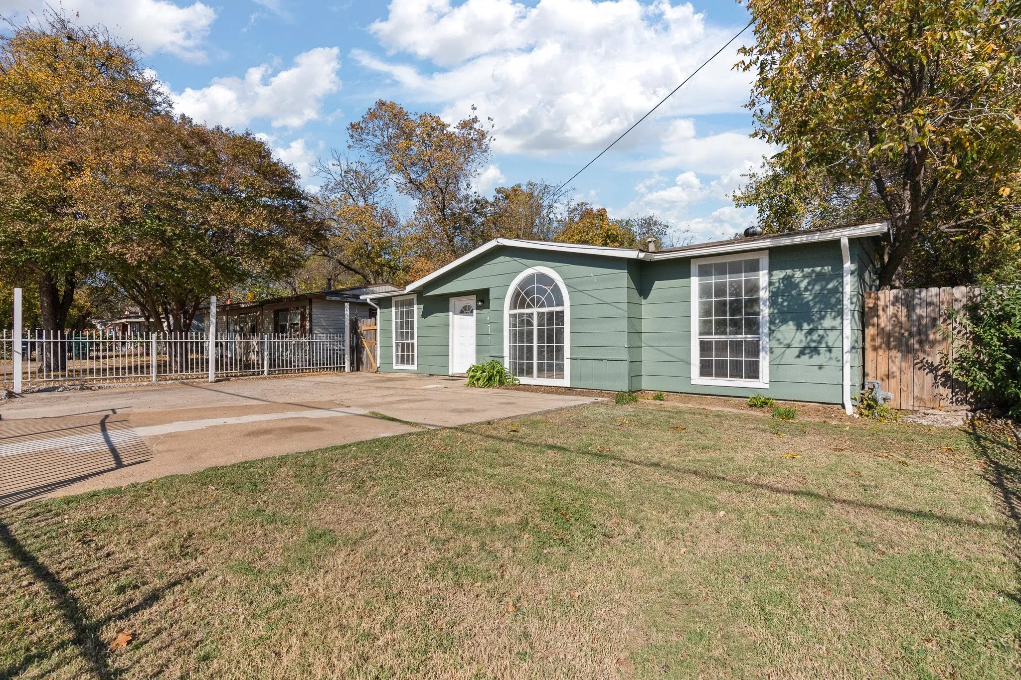 Front exterior with green siding, white trim, arched window, and grid windows