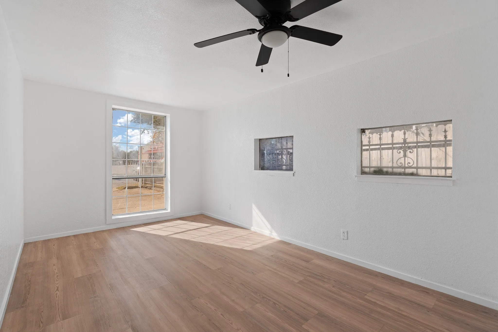 Bright room with wood-finish flooring and a black ceiling fan