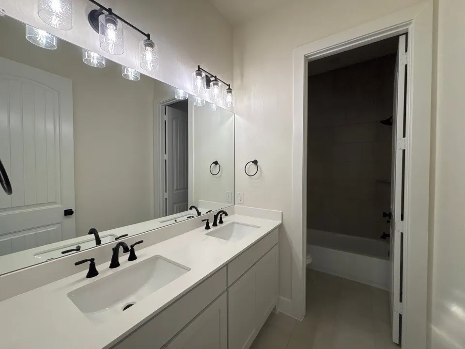 Dual vanity with integrated sinks, matte black fixtures, and light-toned countertop