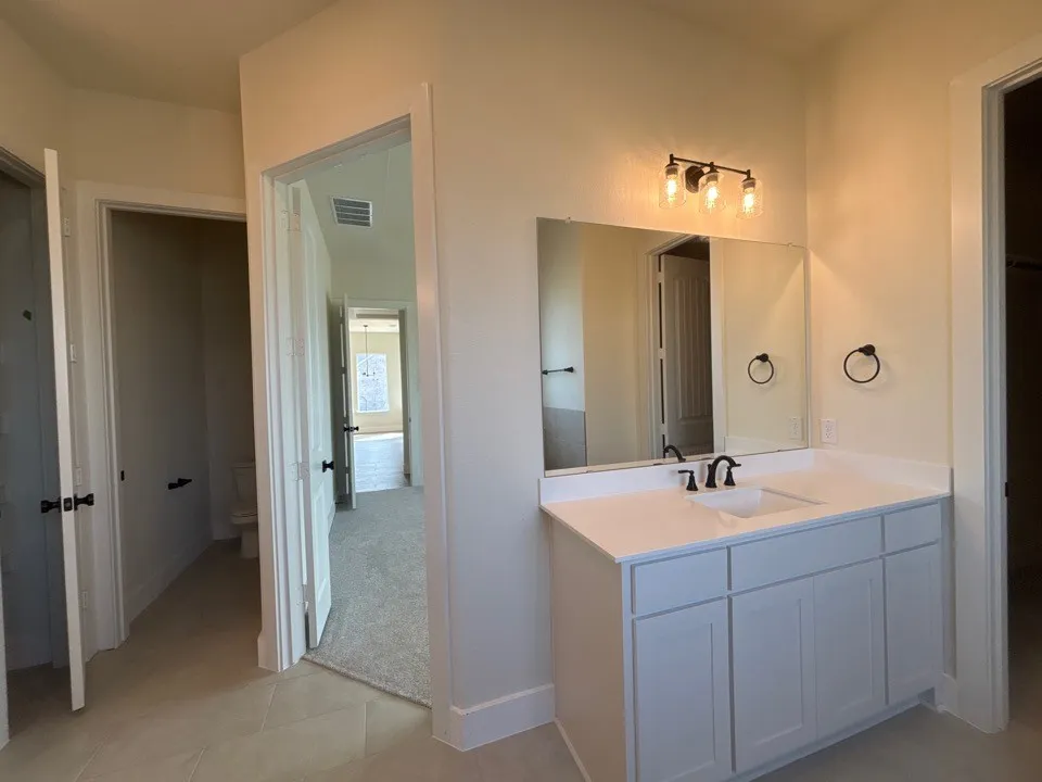 White vanity with an integrated rectangular sink, white countertop, and matte black hardware