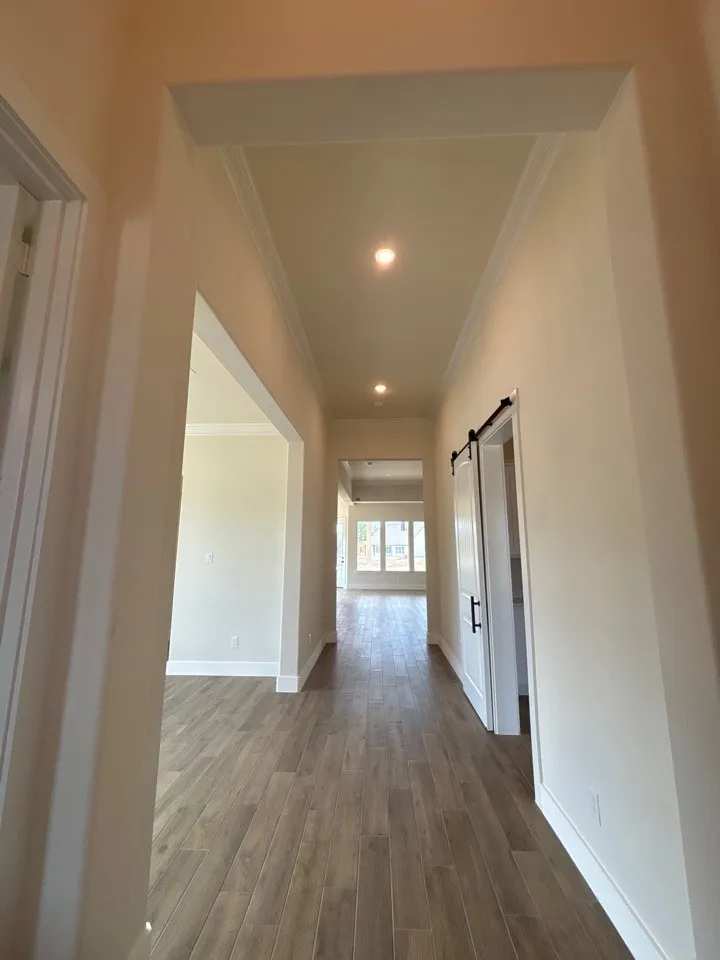 Hallway featuring wood-finish flooring, recessed lighting, crown molding, and a barn door