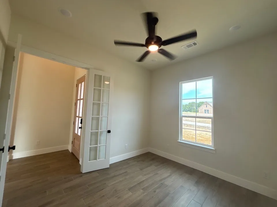 Wood-finish flooring, recessed lighting, ceiling fan, and French doors with matte black hardware