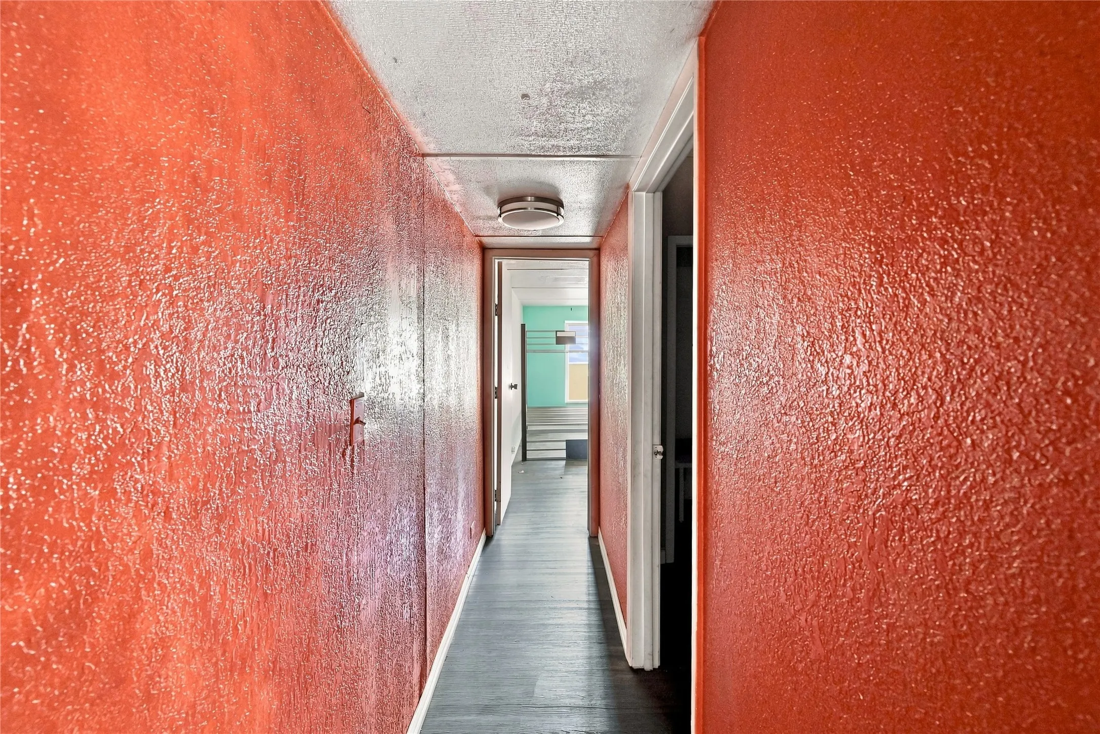 Hallway featuring textured walls and dark wood-finish flooring