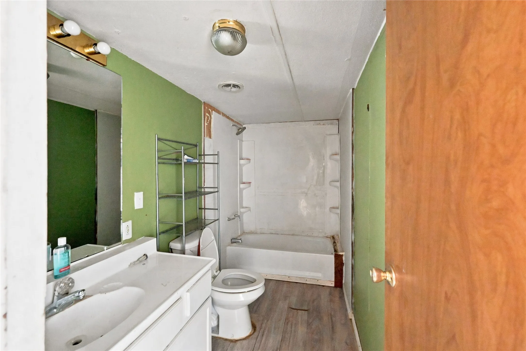 White vanity with integrated sink, wall-mounted mirror, and overhead lighting