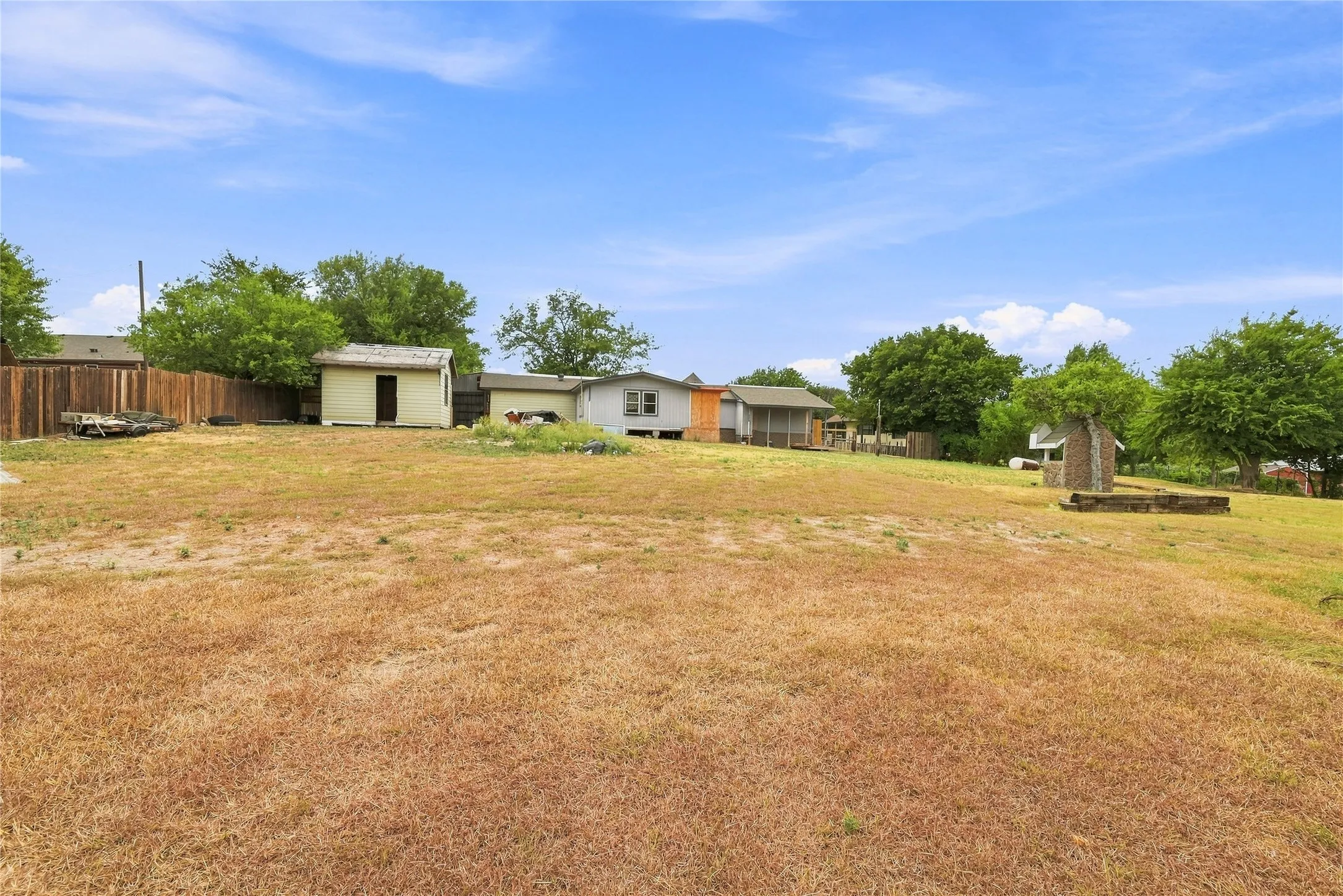 Expansive lot featuring a storage shed, wood fence, and mature trees