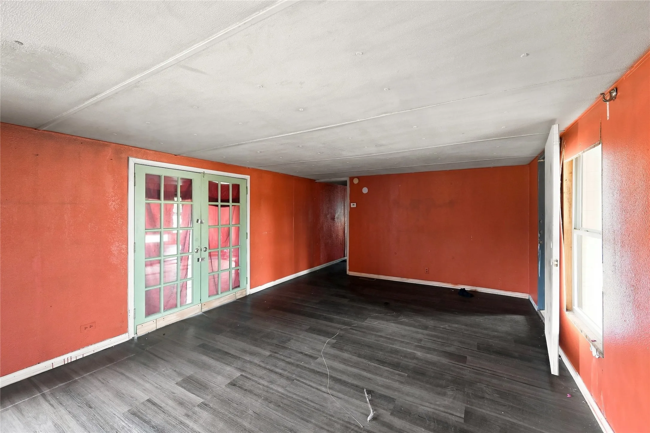 Room featuring wood-finish flooring, a double-paned window, and French doors