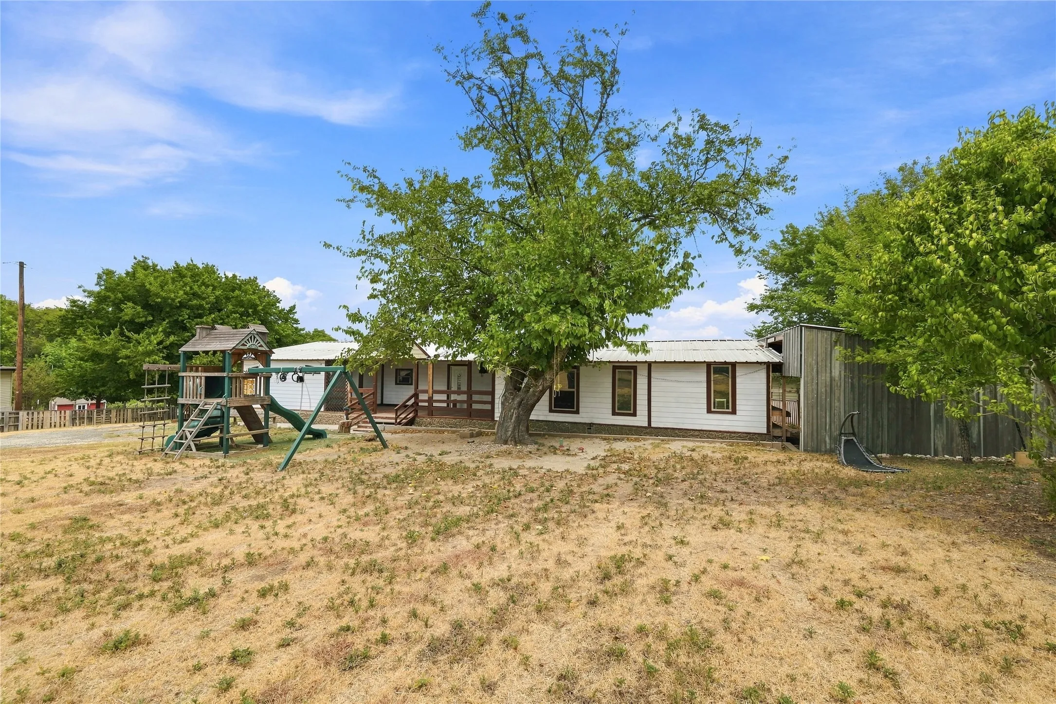 Expansive yard with mature trees and wood-sided structure