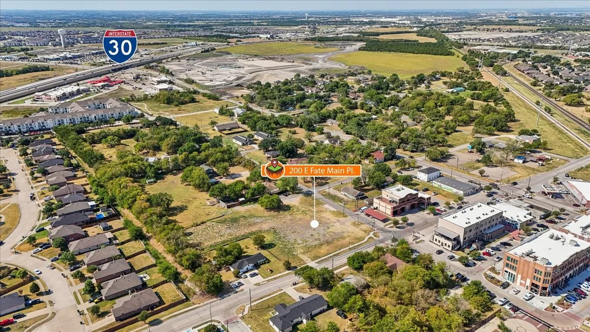 Aerial perspective showcasing a large undeveloped parcel with surrounding residential and commercial structures