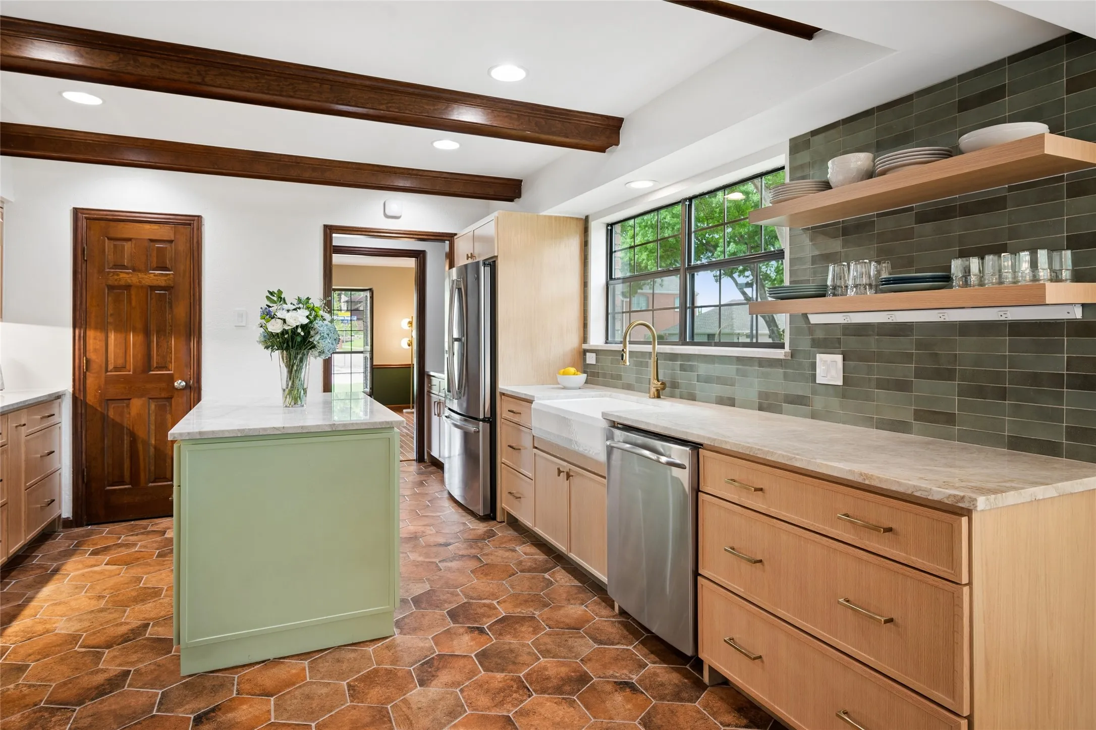 Fully updated in 2023, this kitchen echoes the natural beauty outside with green tile backsplash, wood beamed ceilings, and earthy toned tile floors.