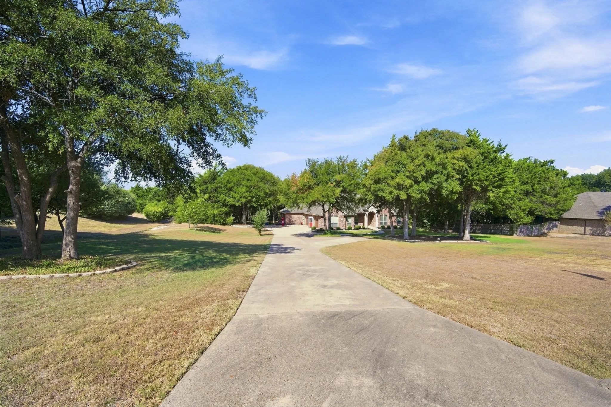 Long paved driveway winds through the property, framed by open green space.