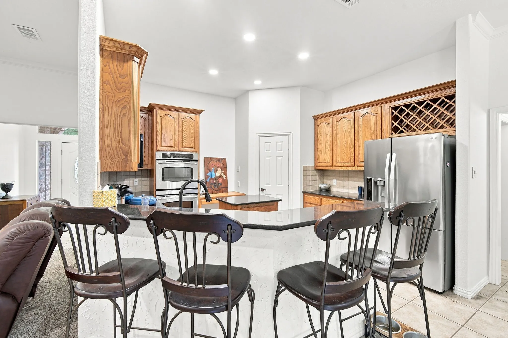 Chef-ready kitchen boasting rich wood cabinetry, a built-in wine rack, and a spacious island with breakfast bar seating.
