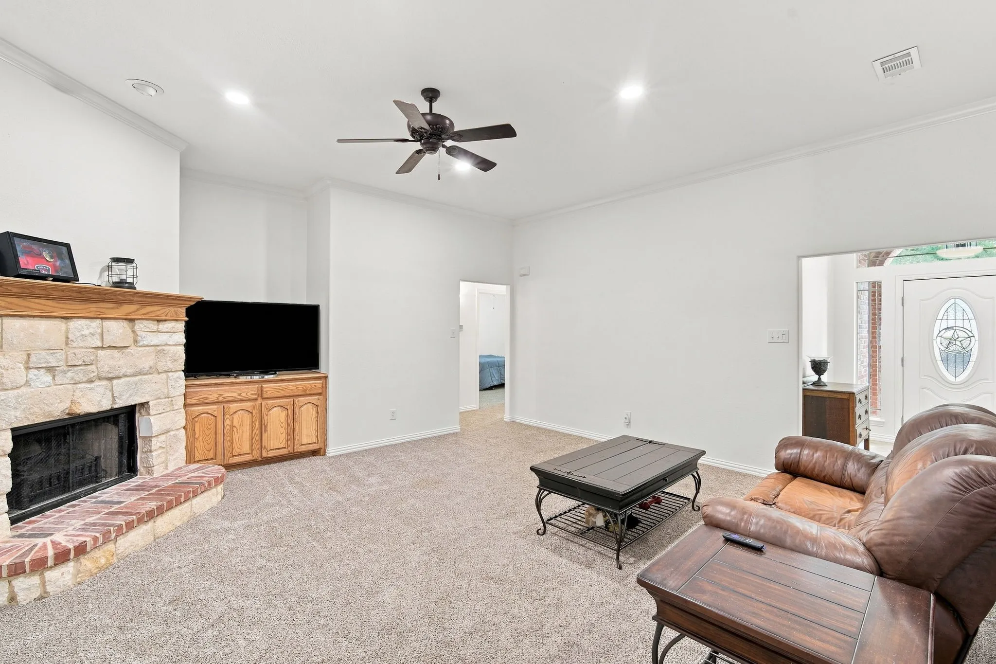 Inviting living space featuring a stone fireplace, brick hearth, and custom wood-finish built-in cabinetry.