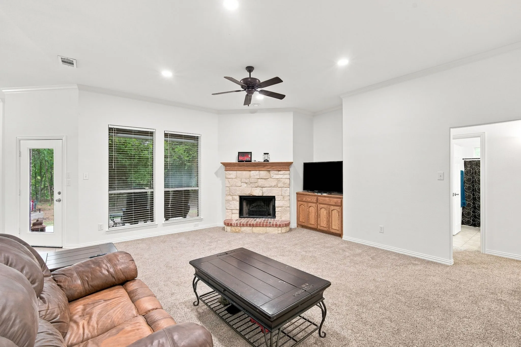 Cozy living room anchored by a striking stone fireplace with a brick hearth and warm wood mantel.