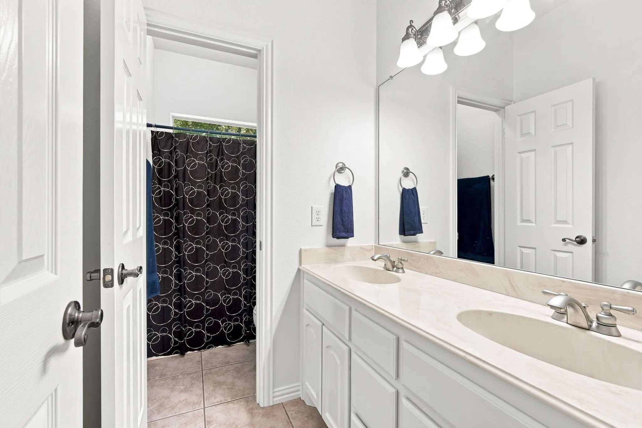 Elegant bathroom featuring a dual vanity, brushed nickel fixtures, and a polished stone countertop.
