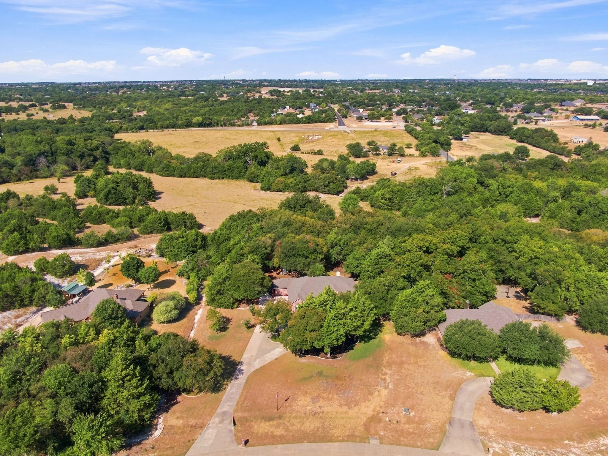 Sweeping aerial view showcasing the property's expansive, tree-covered acreage and private driveway, a true rural retreat.