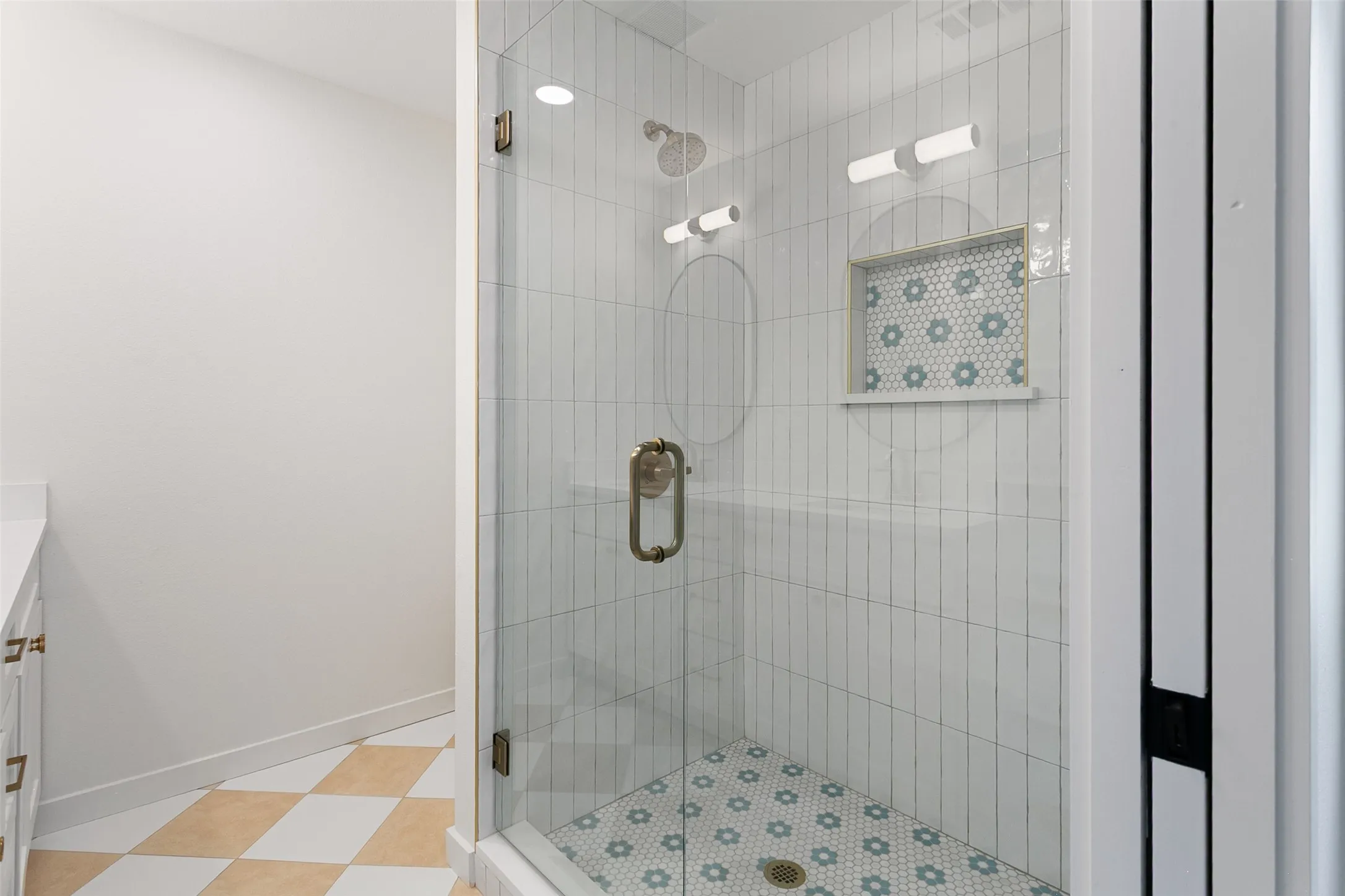 Glass-enclosed shower with vertical subway tile walls and a decorative tiled niche