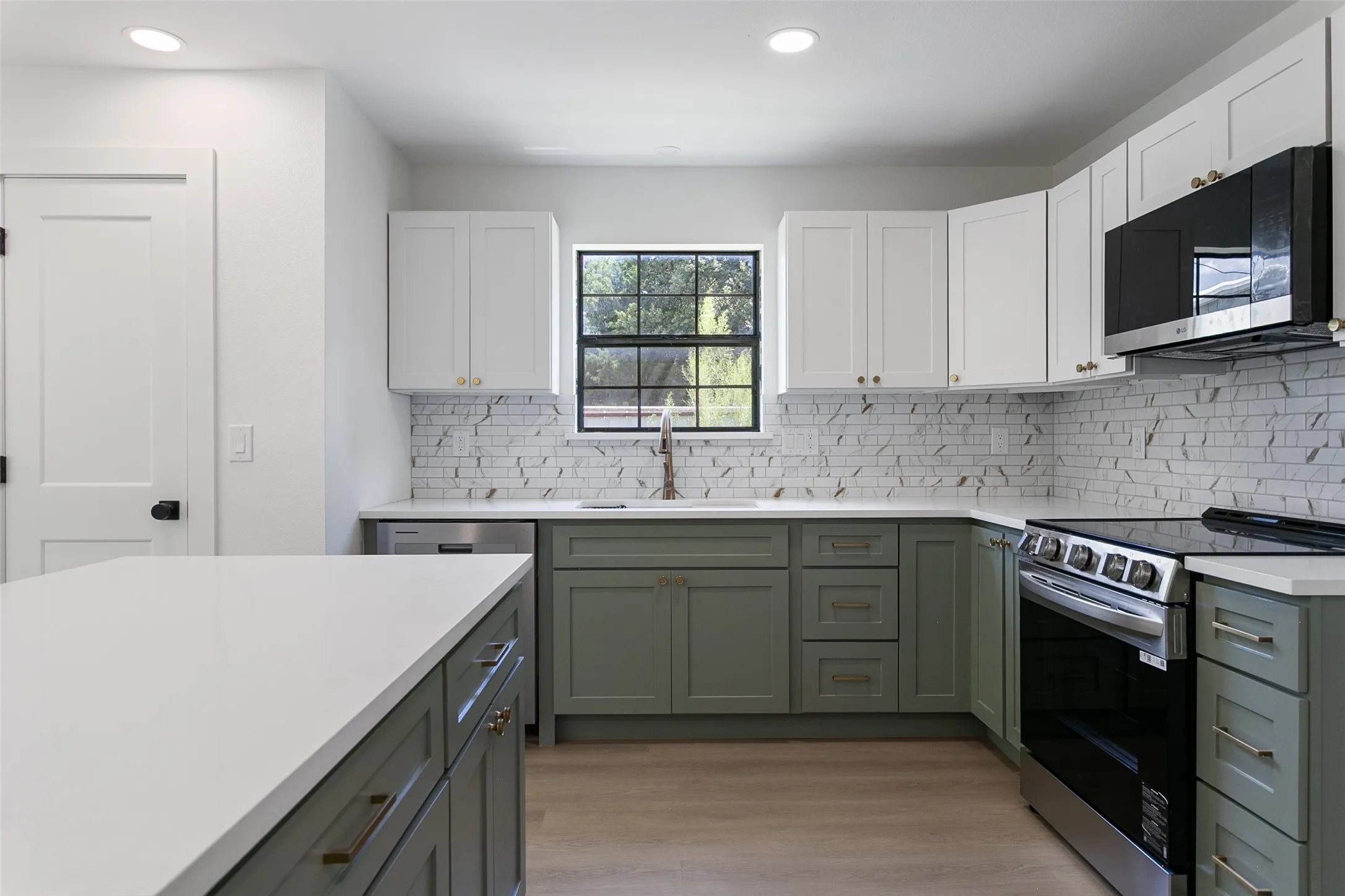 Kitchen featuring dual-tone cabinetry, stainless steel appliances, and wood-finish flooring