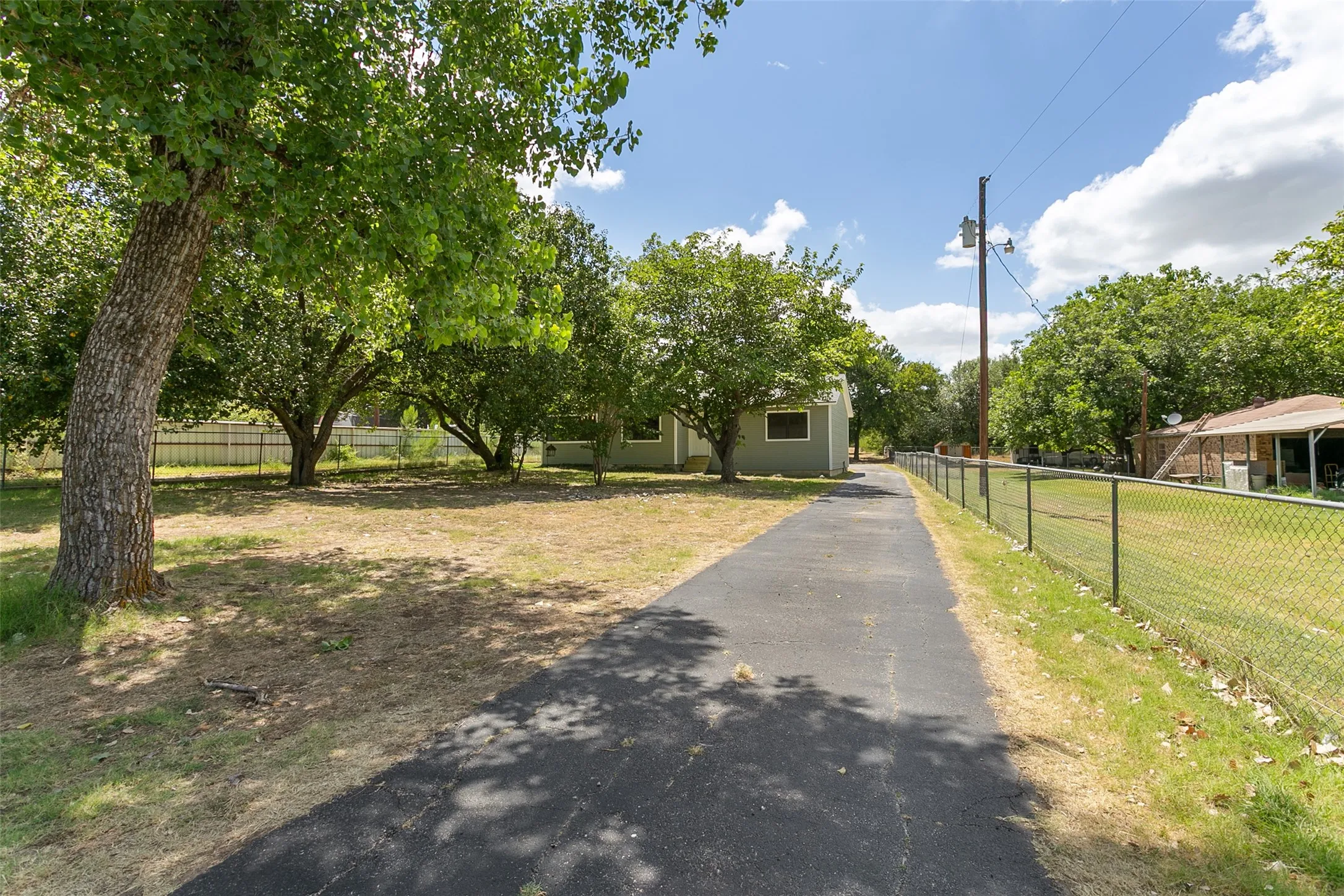 Paved driveway leading to a residence with a light-colored exterior