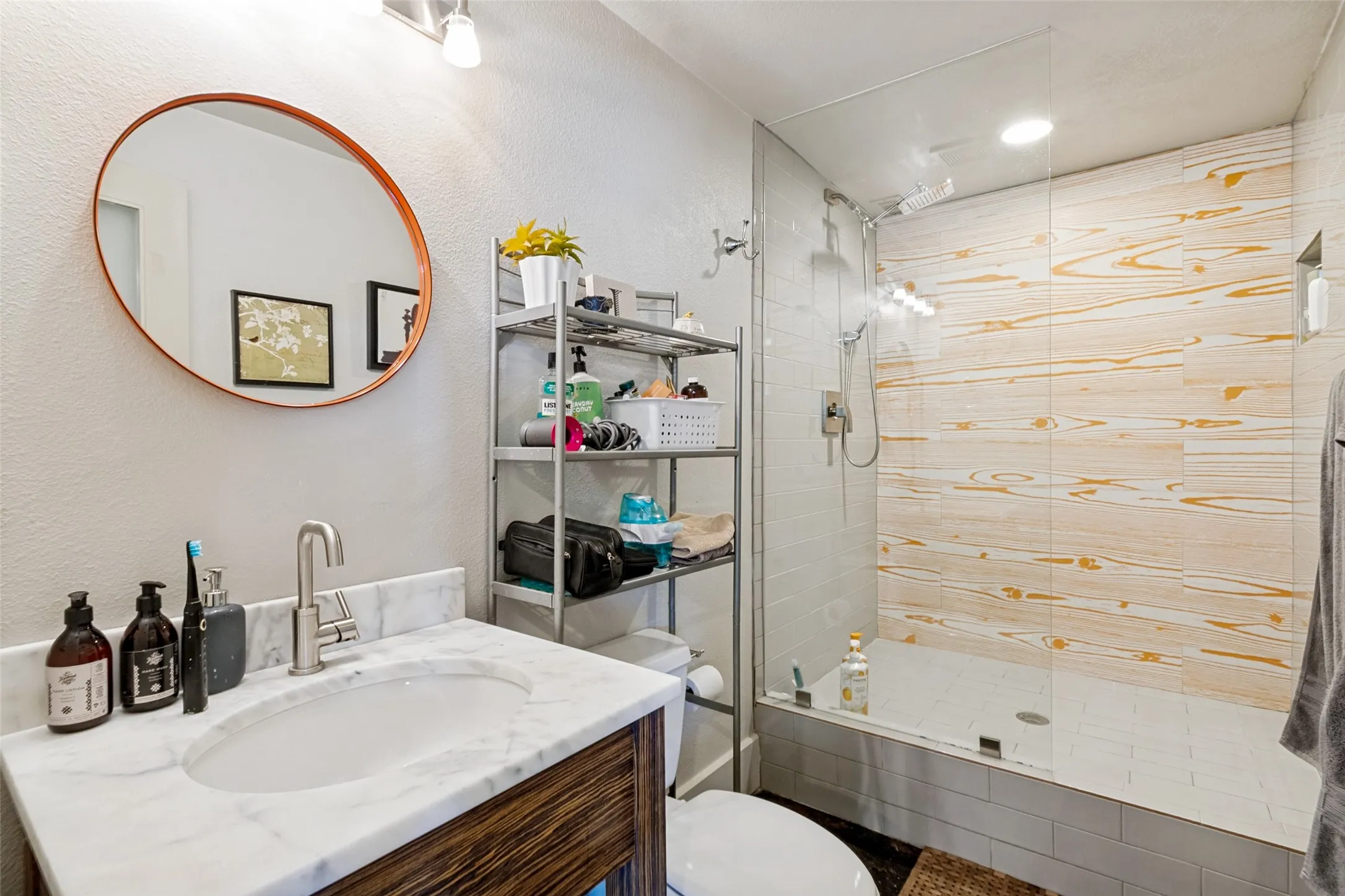 Updated  with an oval mirror and white under-mount sink with a single-handle faucet, set into a white marble-look countertop