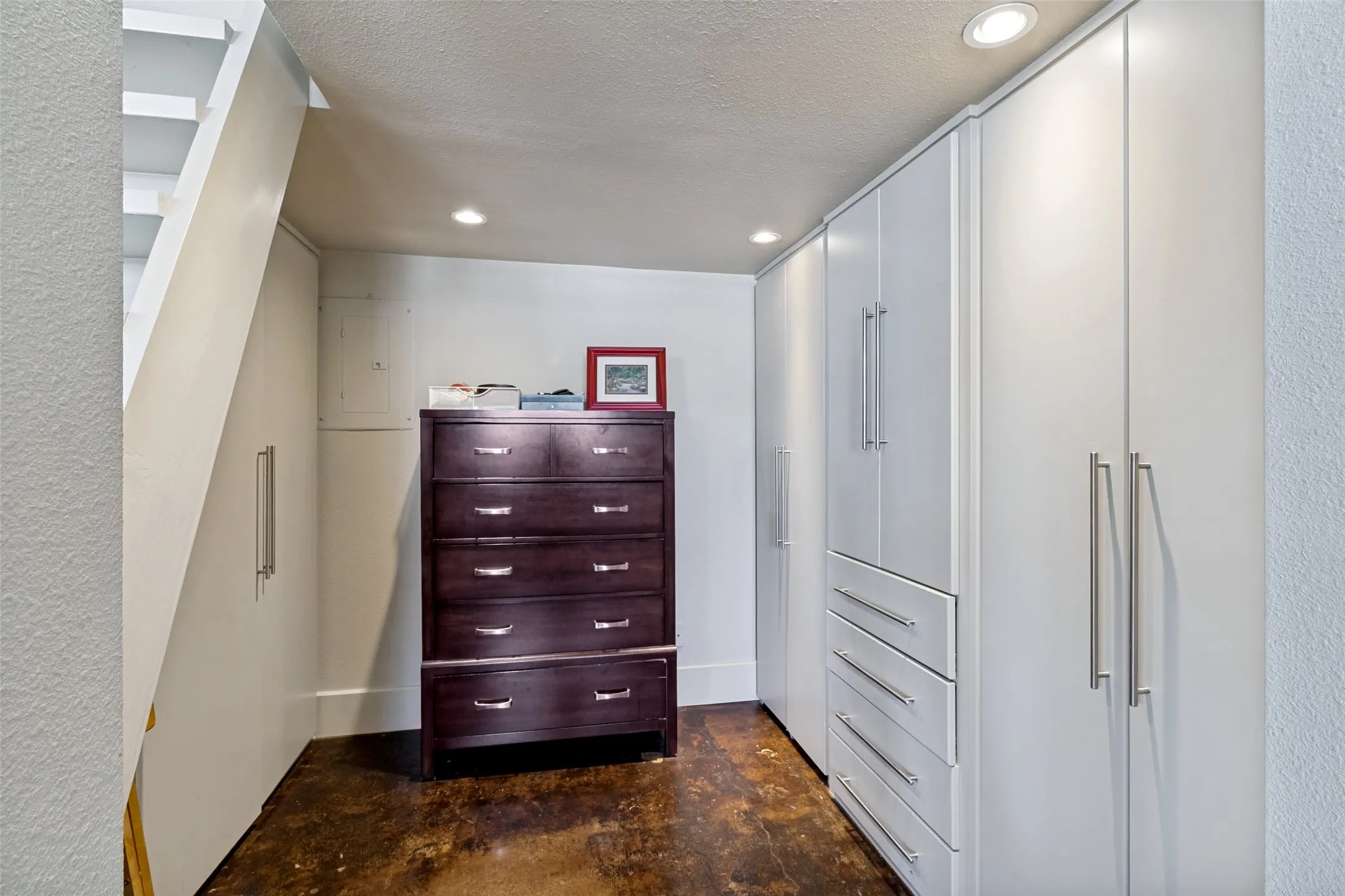 Integrated white cabinetry with brushed nickel hardware, recessed lighting, and a textured flooring surface