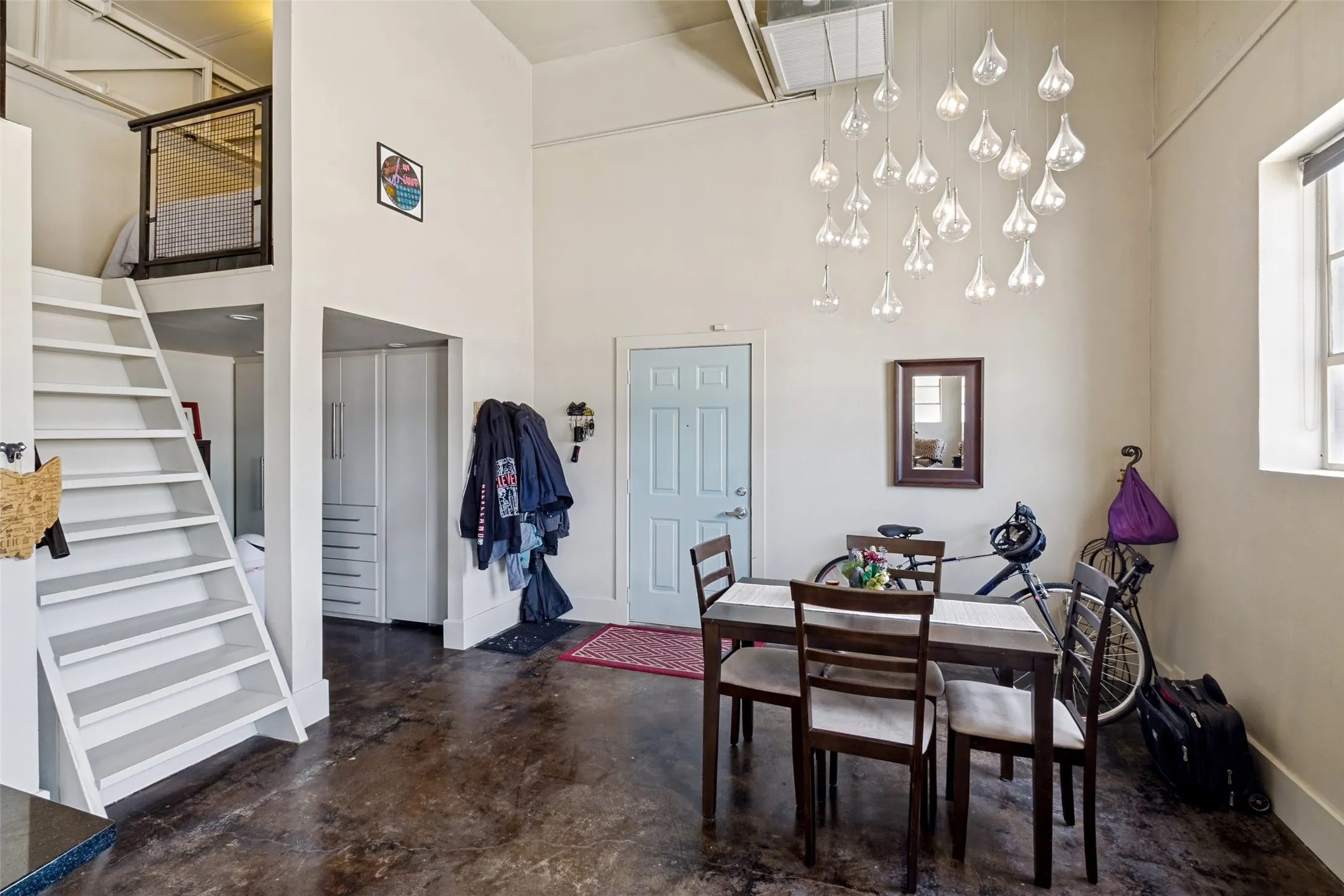 High ceilings, polished concrete flooring, a custom decorative light fixture, built-in storage, and a lofted space