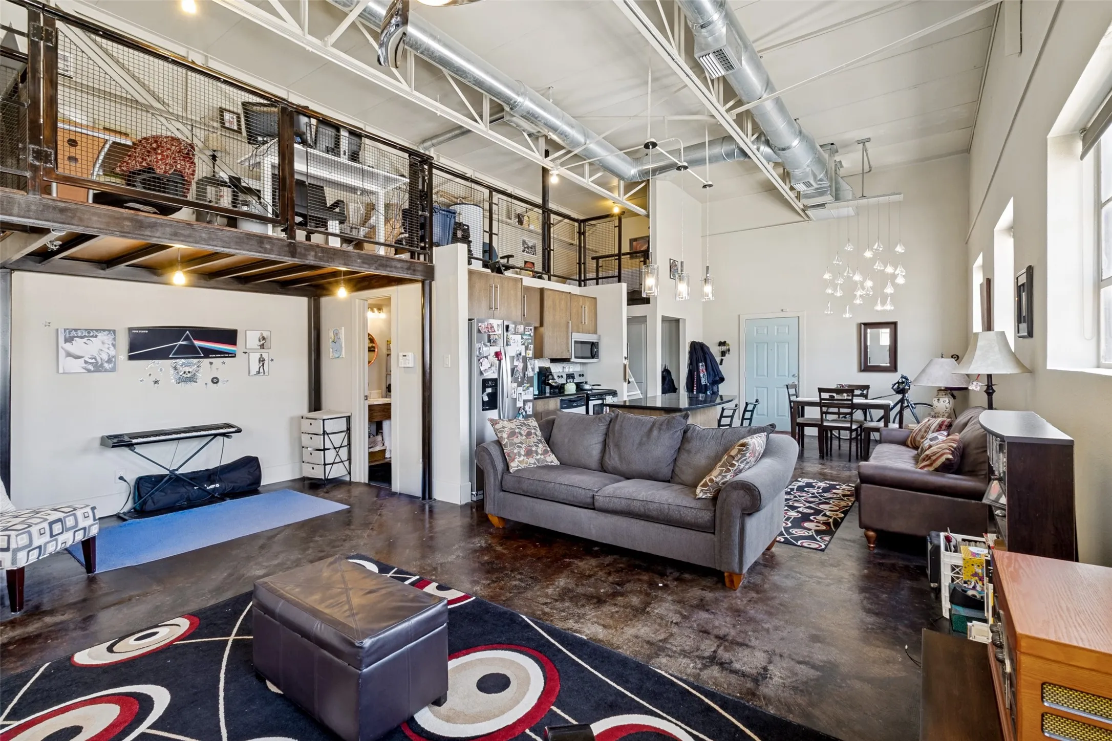 Open-concept living space with exposed ductwork, a mezzanine level, high ceilings, a built-in kitchen island, and concrete flooring