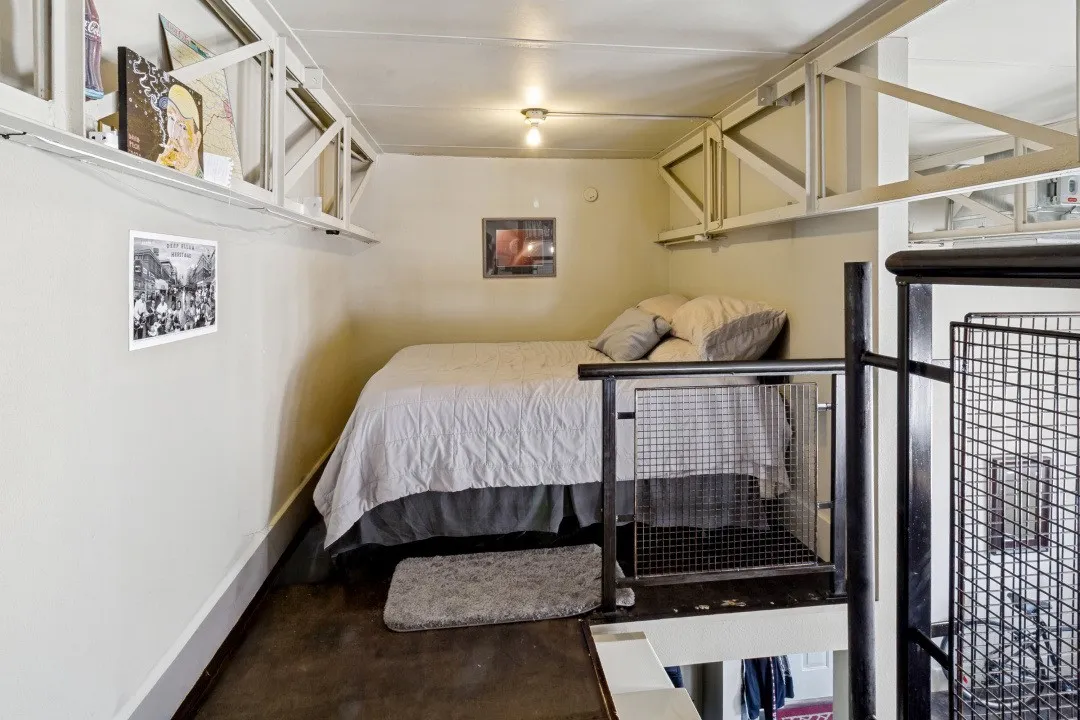 Mezzanine loft featuring a built-in bed platform, industrial-style railings, exposed structural beams, and integrated overhead shelving