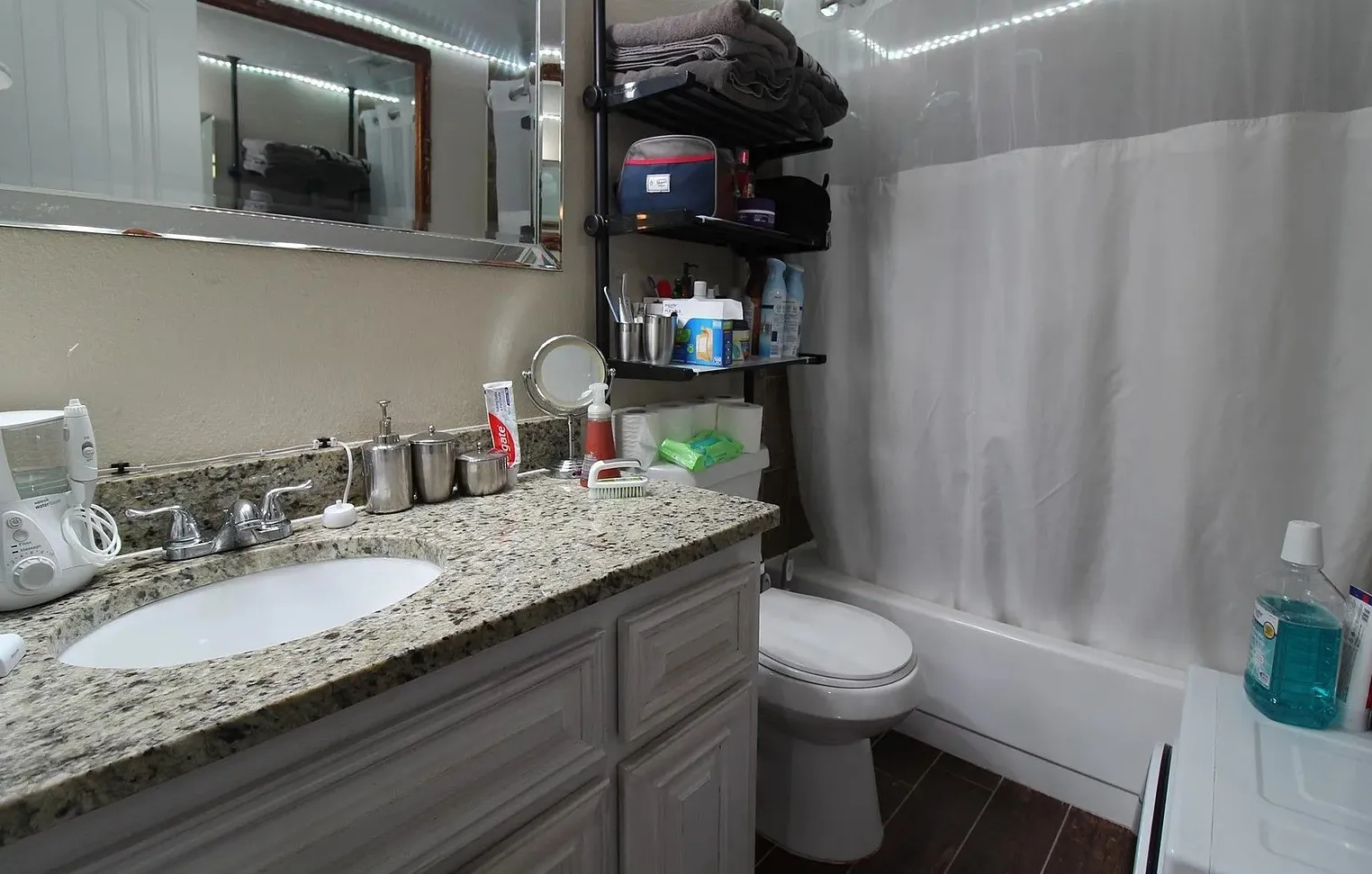 Vanity with an integrated sink, granite-style countertop, and wood-finish flooring