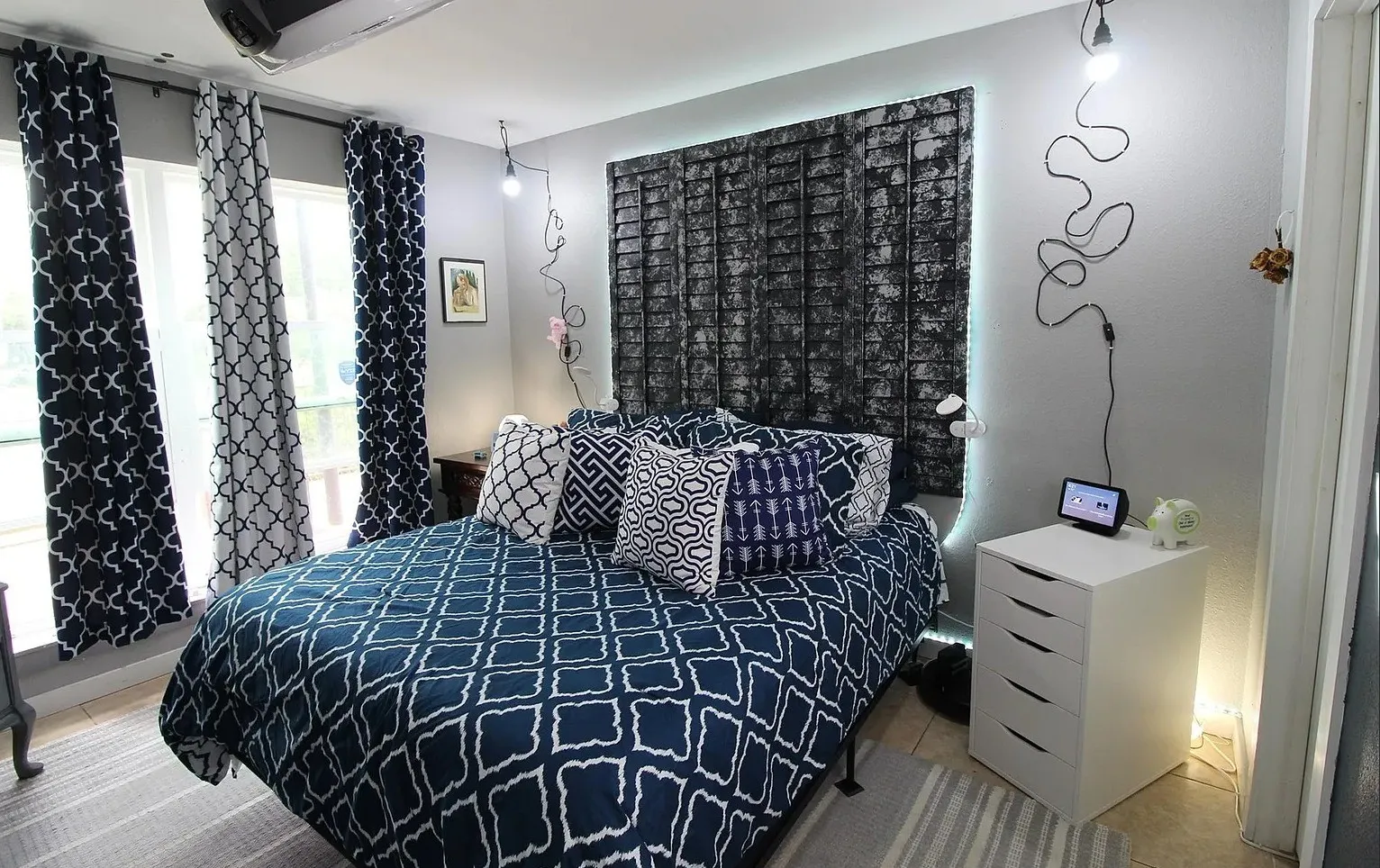 Wall-mounted decorative lighting fixtures, overhead ceiling fan, and large windows with privacy drapes