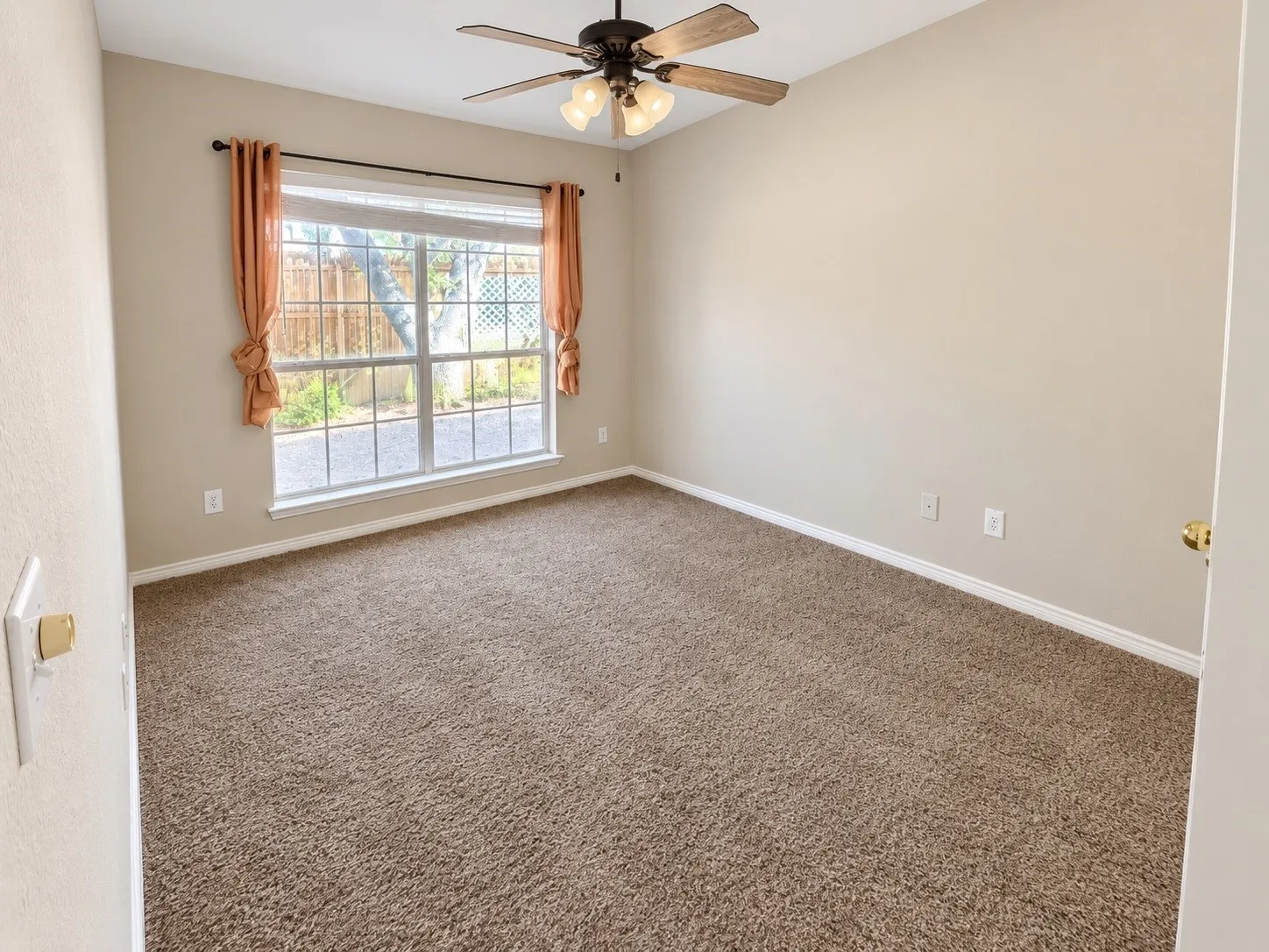 Carpeted room with a large window, a ceiling fan with integrated lighting, and neutral wall tones