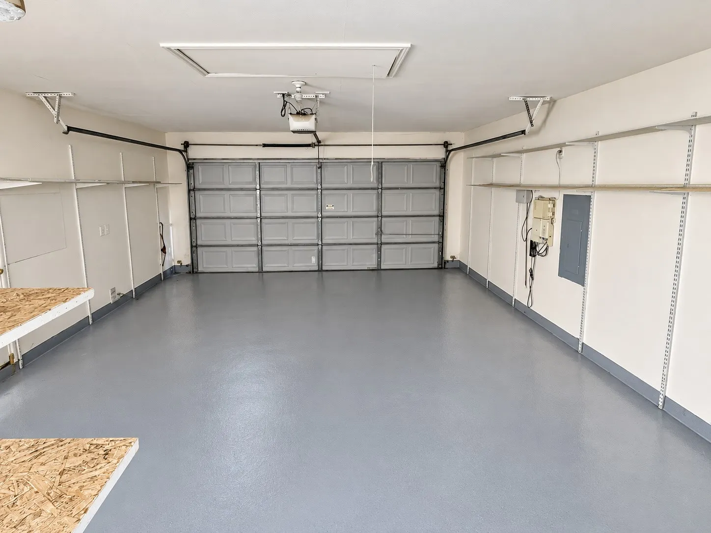 Garage with gray epoxy flooring, built-in shelving, and an automatic garage door opener