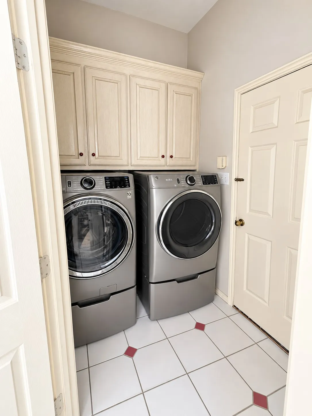 White tile flooring with red accent tiles, built-in cream cabinetry, and light-toned walls