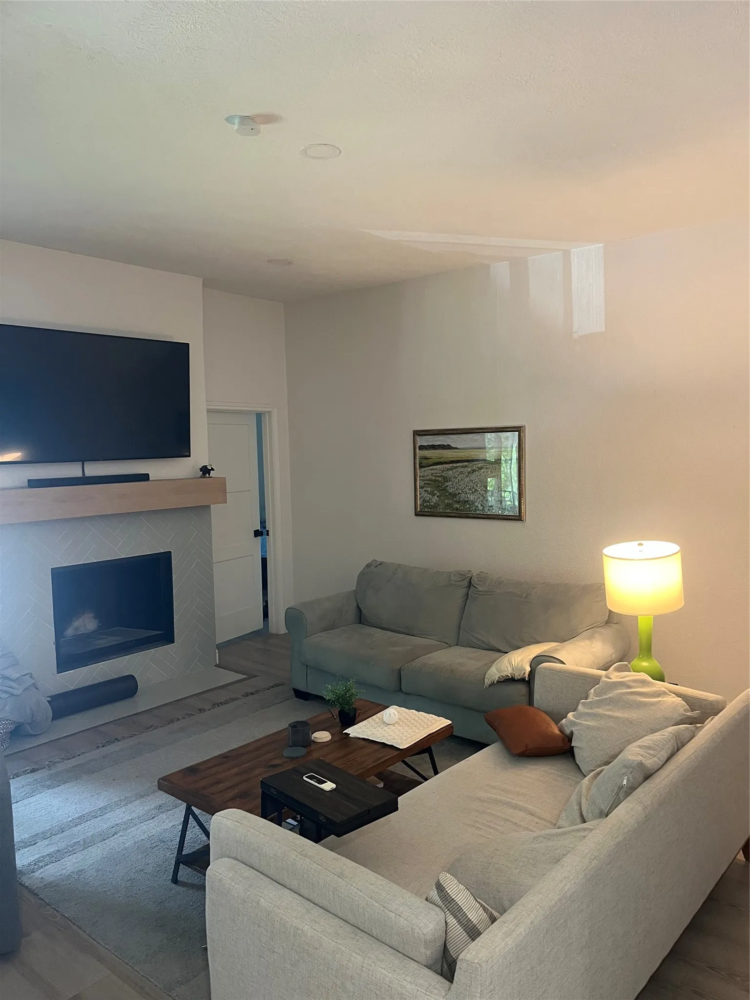 Living area featuring a modern fireplace with a light-toned tile surround and a wood mantel