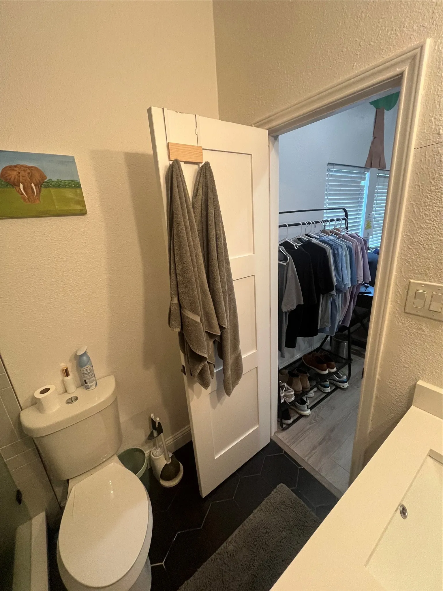 Bathroom featuring black hexagonal floor tiles and a white toilet