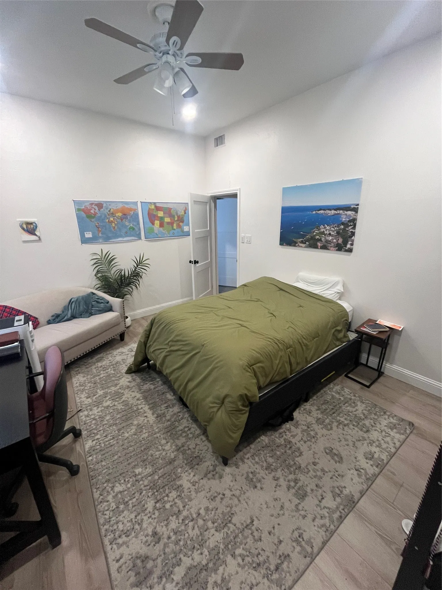 Spacious room featuring wood-finish flooring, a contemporary ceiling fan, and white walls