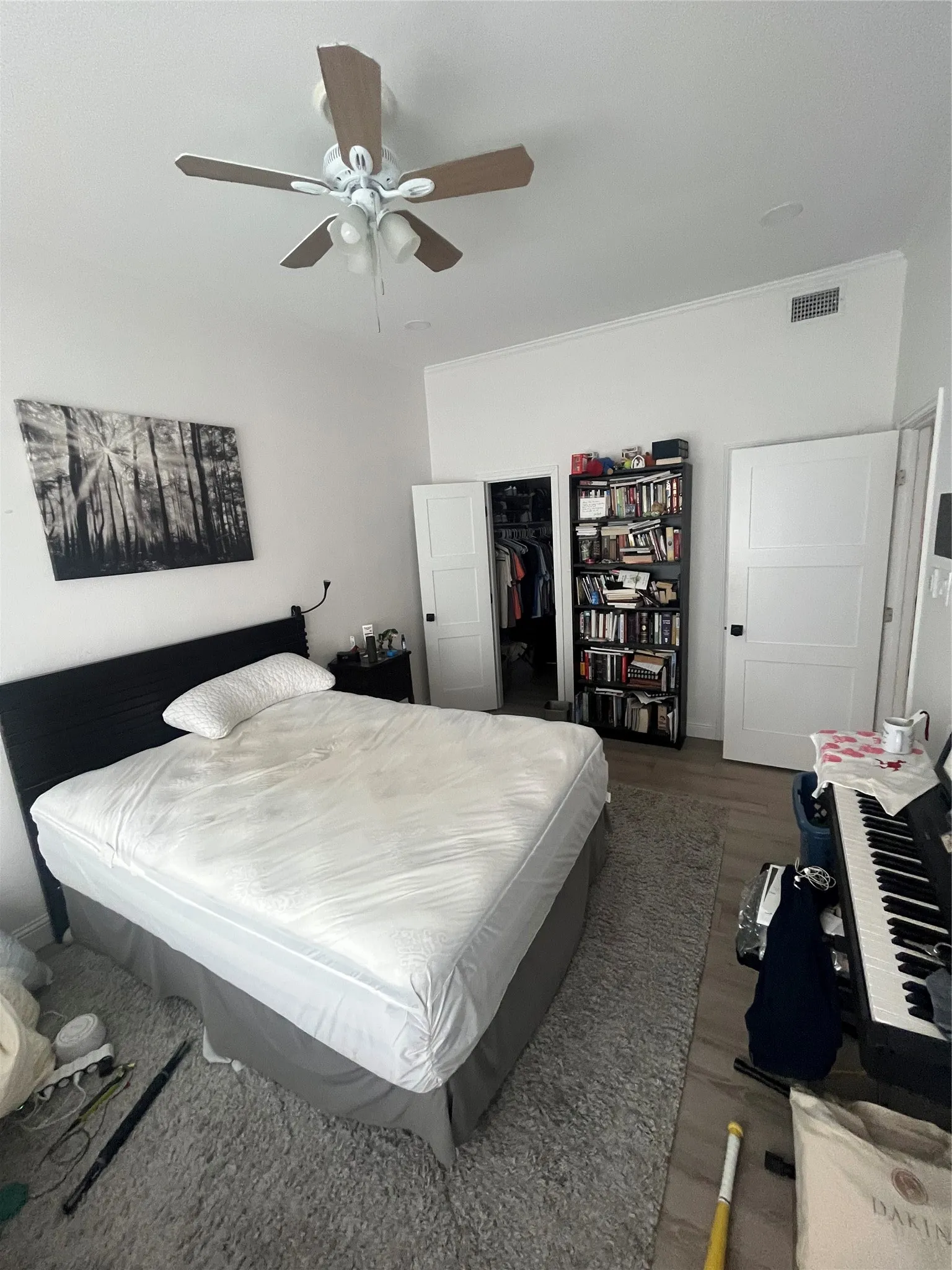 Bedroom featuring wood-finish flooring, a ceiling fan with integrated lighting, and white panel doors