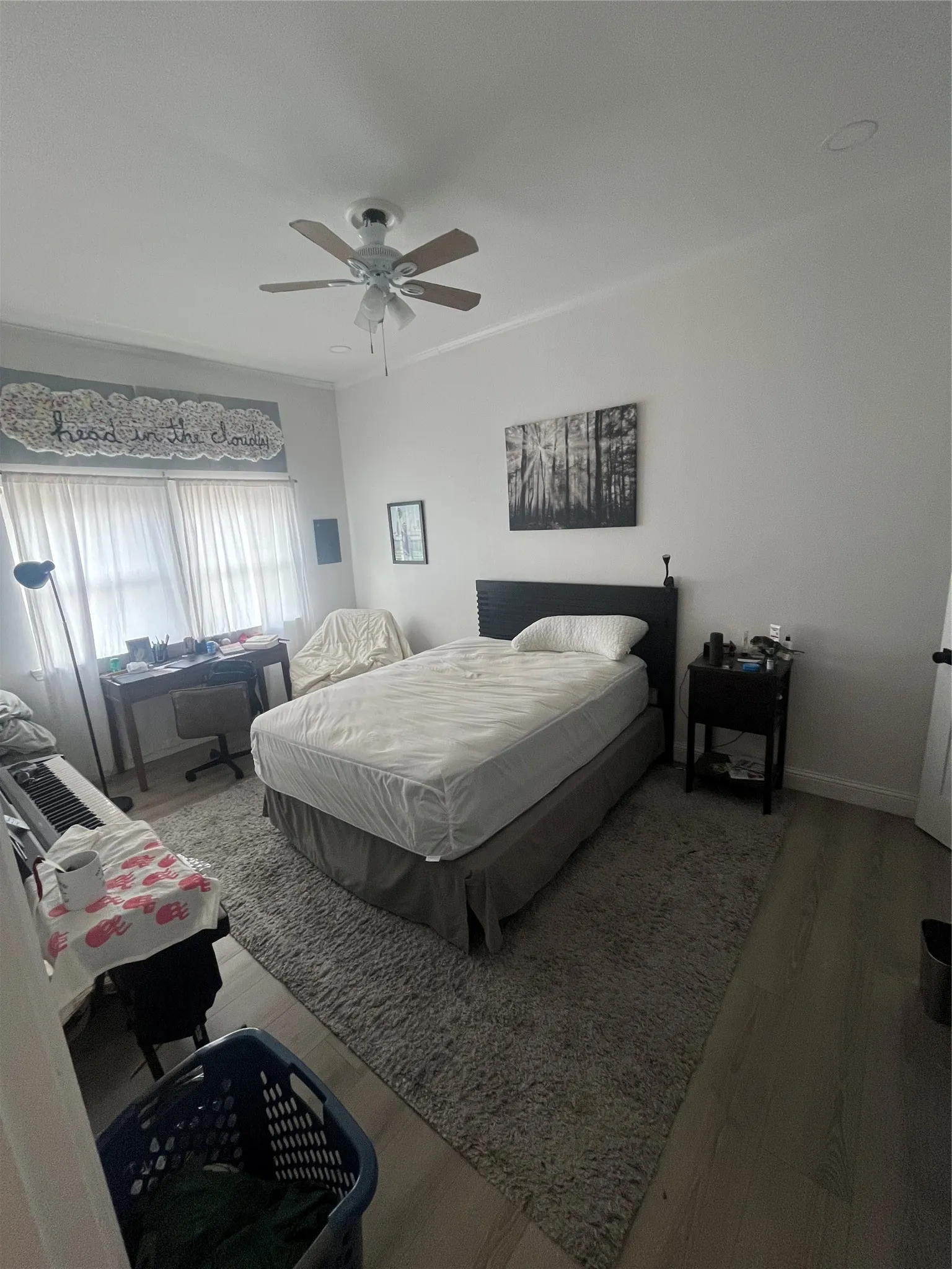 Bedroom featuring light wood-finish flooring, a ceiling fan with integrated lighting, and crown molding