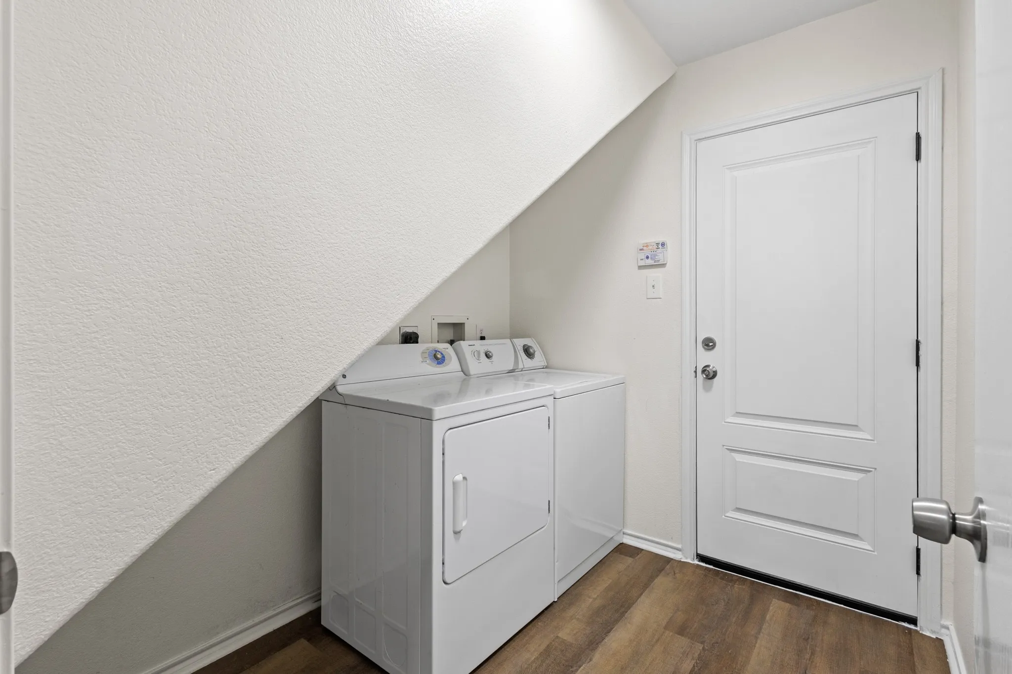 Dedicated utility area featuring wood-finish flooring and a paneled door