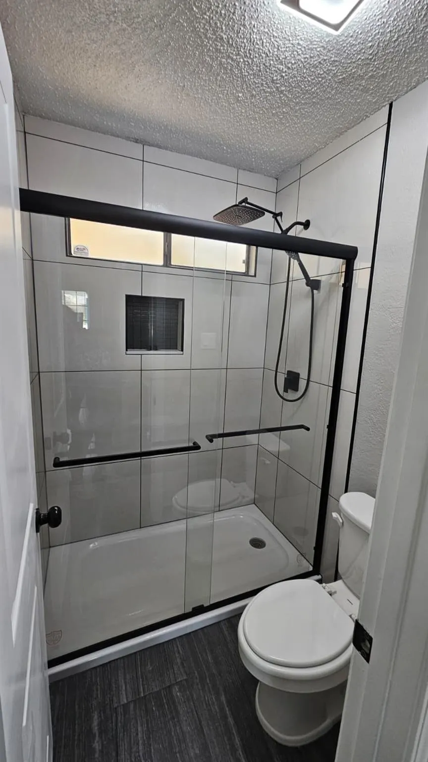 Contemporary shower enclosure with matte black hardware, white subway tile surround, integrated niche, and a rain showerhead