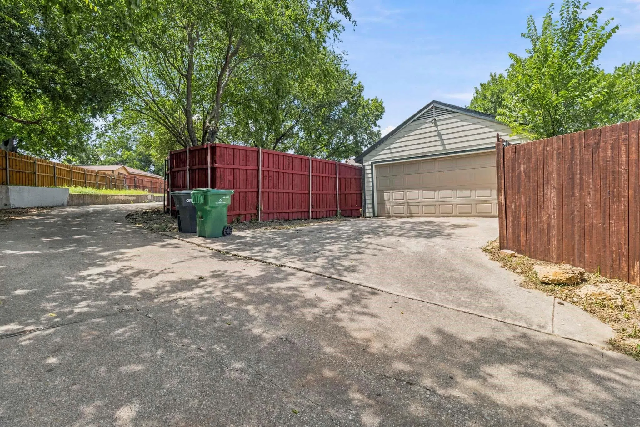Attached garage with horizontal siding and a panel garage door, concrete driveway, and wood fencing
