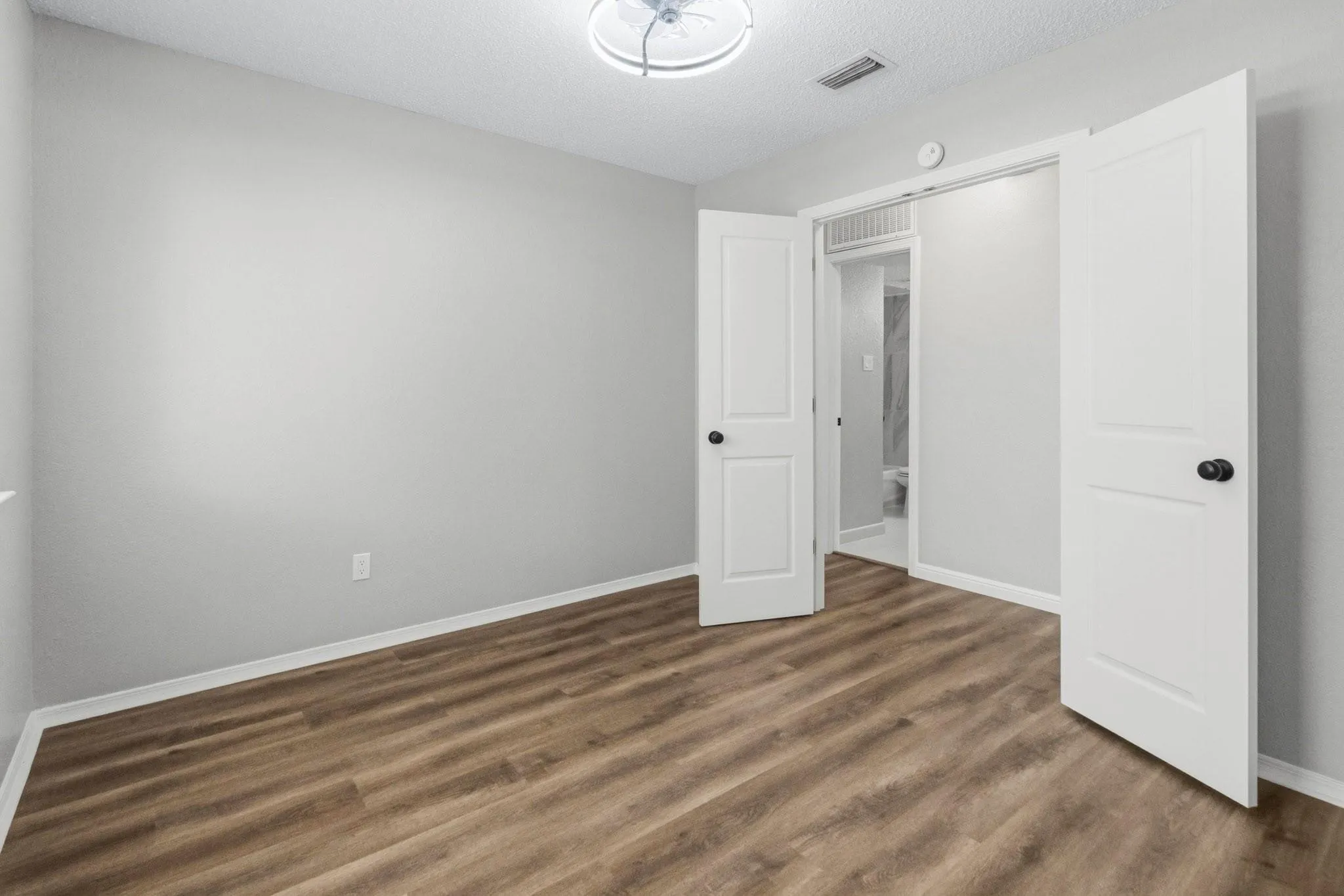 Room featuring wood-finish flooring, white trim, and a ceiling-mounted light fixture