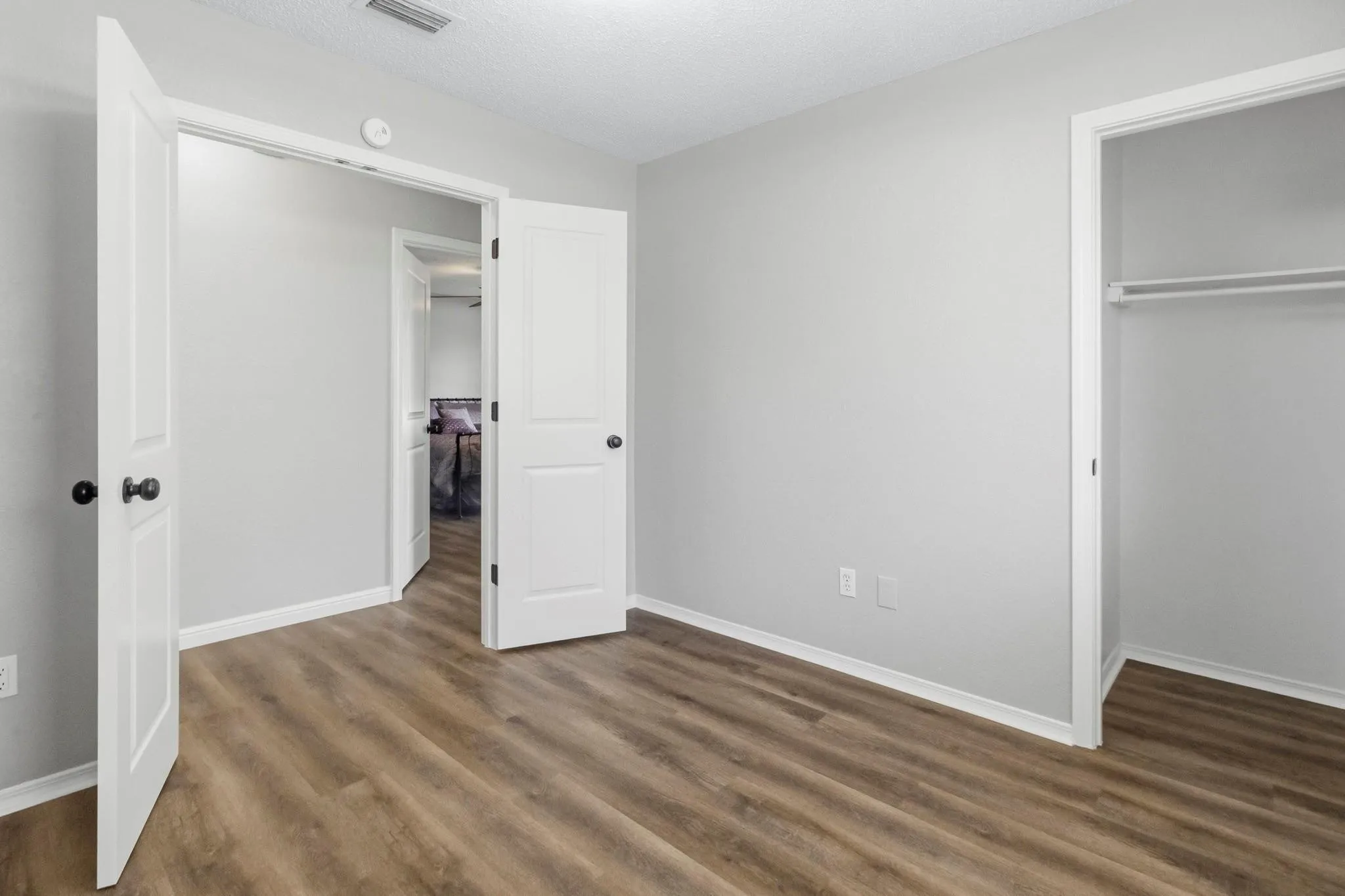 Wood-finish flooring, light gray wall paint, and a built-in closet with shelving