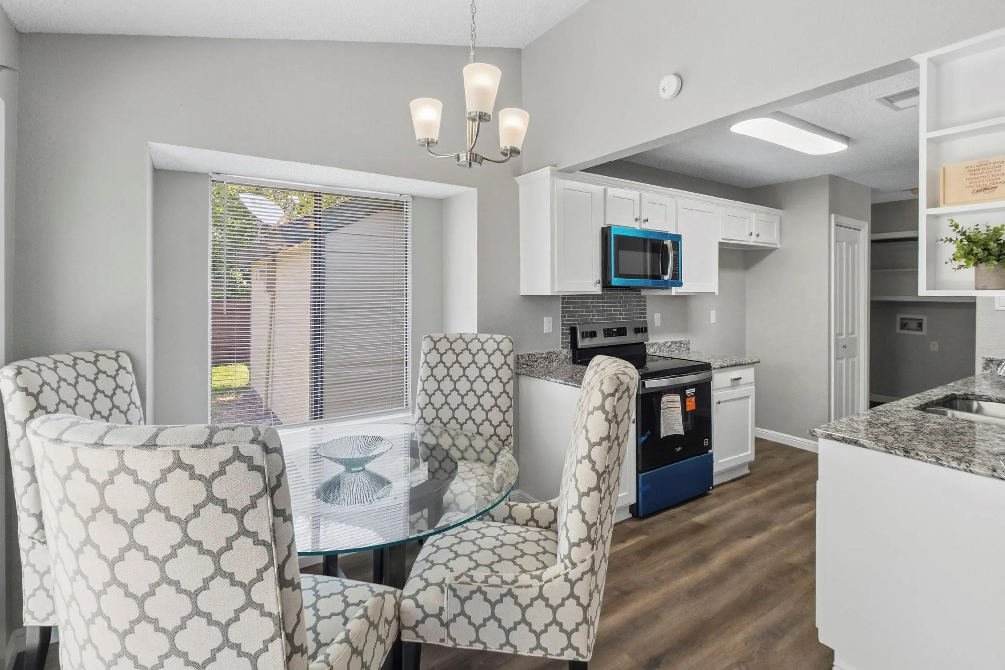 Kitchen featuring white cabinetry, granite-style countertops, mosaic tile backsplash, and wood-finish flooring