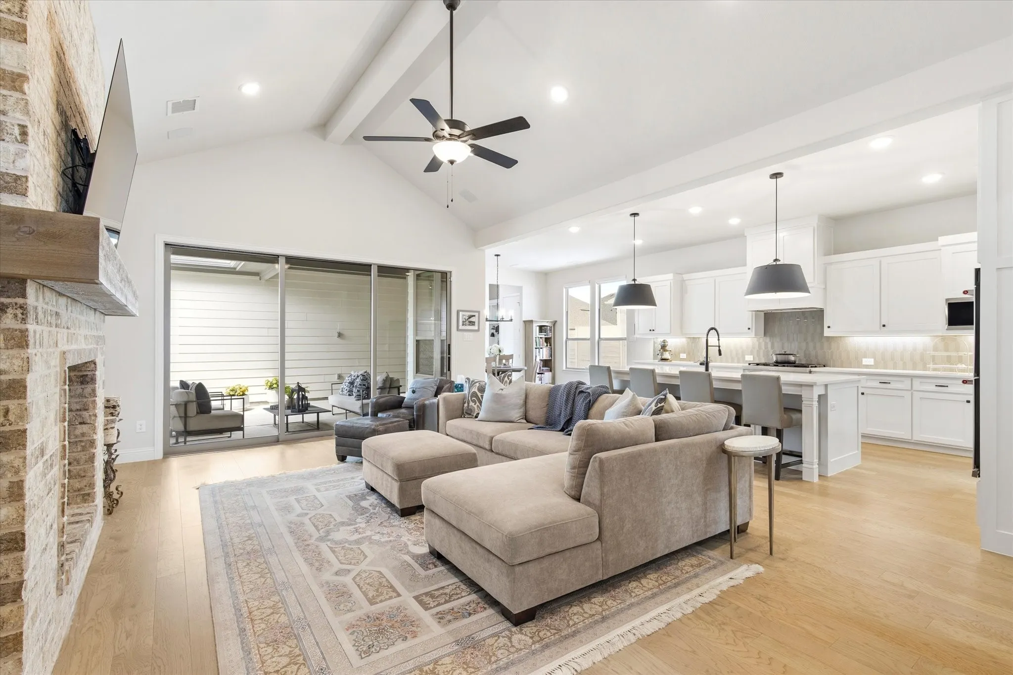 Cozy Living Area that opens into the Kitchen.  Brick Fireplace, wood flooring and Vaulted ceilings.  Sliding doors exit to the rear patio.